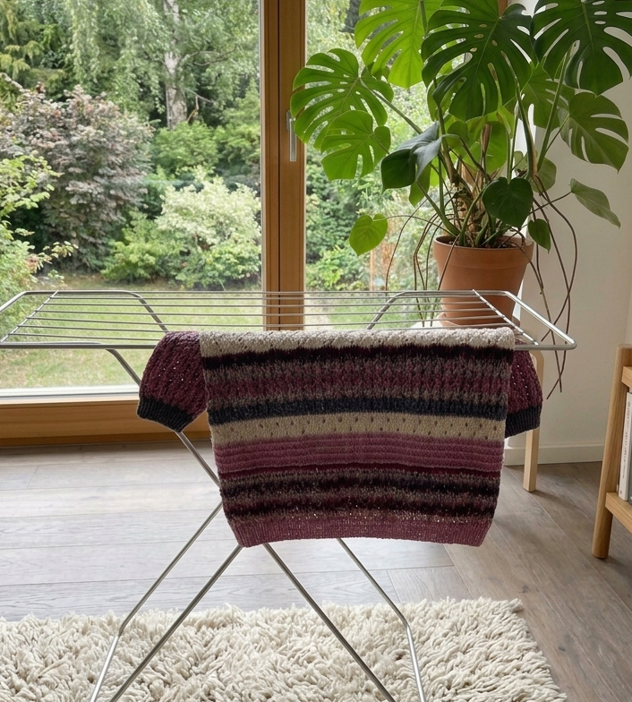 Ein gestrickter Pullover trocknet flach liegend auf einem Tuch